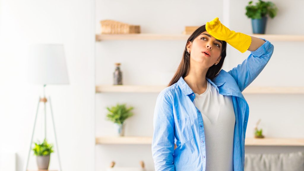 Tired woman cleaning floor with string mop